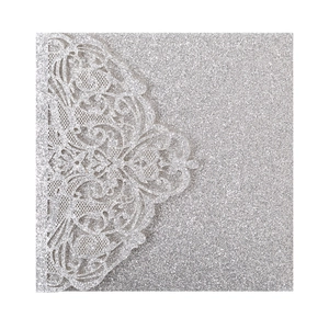 Macro shot of laser-cut lace pattern and sparkling silver glitter on square invitation