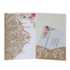 Detail of laser-cut glitter gold wedding invitation with intricate lace patterns and floral insert
