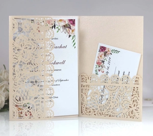 Close-up of laser-cut champagne gold wedding invitation with floral lace pattern