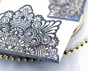 Macro detail of laser-cut paisley hollow wedding invitation in navy glitter paper