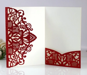 Close-up of laser cut red glitter wedding invitation with floral hollow pattern