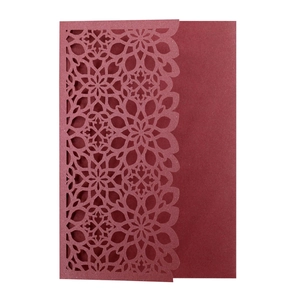 Macro detail of laser-cut burgundy wedding invitation featuring intricate mandala patterns
