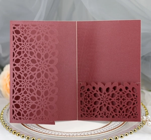 Detail of laser-cut floral pattern on elegant burgundy wedding invitation with pocket
