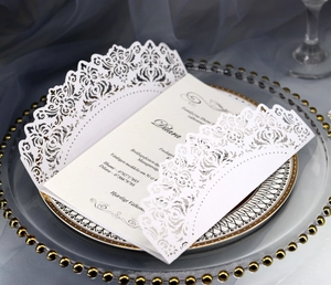 Elegant white laser-cut wedding invitation with intricate floral lace and inner card