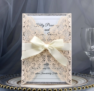 Close-up of laser cut wedding invitation with butterfly patterns and satin ribbon bow