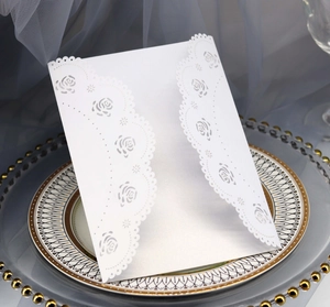 Detail of white laser-cut rose hollow invitation card on an elegant ceramic plate