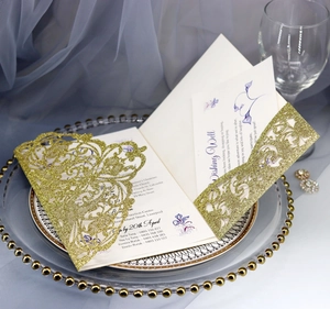 Detail of laser-cut gold glitter wedding invitation with floral lace pattern and inner card