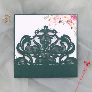 Macro detail of laser-cut lace pattern on forest green wedding invitation card