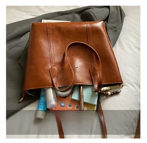 Macro shot of large capacity brown leather tote bag interior with tablet and books