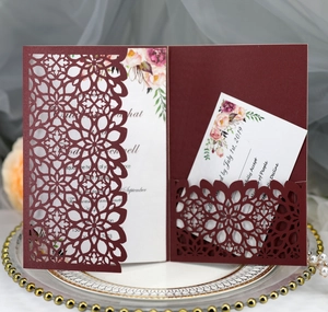 Detail of burgundy laser-cut wedding invitation with elegant floral cards and RSVP note