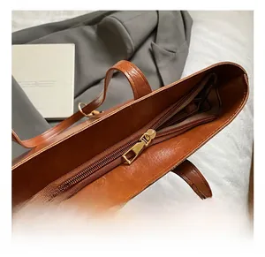 Detail of premium golden metal zipper and smooth brown leather texture on a tote bag