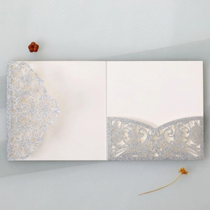 Detailed laser-cut silver glitter wedding invitation featuring intricate scroll lace pattern