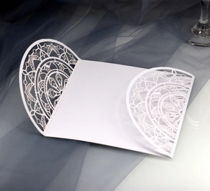 Nahaufnahme der lasergeschnittenen weißen Hochzeitseinladung mit feiner Spitzen-Mandalatextur