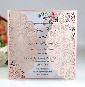 Close-up of laser-cut peacock lace invitation with pink floral inner card details