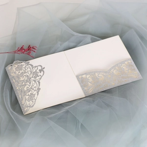 Close-up of laser cut hollow pattern with silver glitter on elegant off-white wedding invite