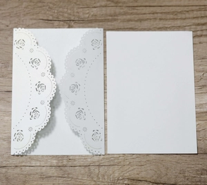 Detail of white laser-cut rose invitation card set with pearlescent finish on wood