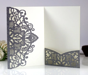 Detail of laser-cut wedding invitation with purple glitter and lace pattern