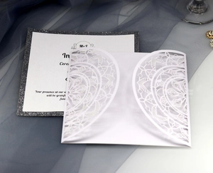Nahaufnahme der lasergeschnittenen Hochzeitseinladung mit silbernem Glitzereinsatz und Spitze