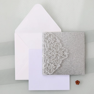 Macro shot of silver glitter laser cut lace invitation with intricate floral hollow pattern