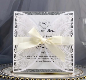 Detail einer lasergeschnittenen Hochzeitseinladung mit silbernem Glitzerrand und Schleife