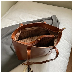 Detailed interior of a brown leather tote bag with striped lining and zipper compartments