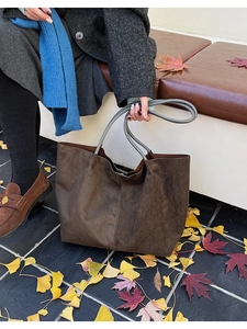 Gros plan d'un grand sac cabas en daim marron avec anses grises sur feuilles d'automne
