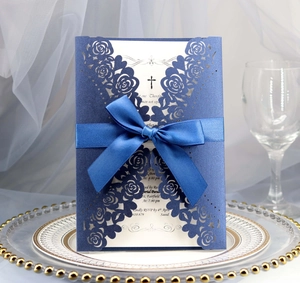 Detail of laser-cut rose hollow invitation card with navy blue silk ribbon and elegant bow