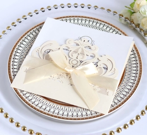 Exquisite laser-cut lace wedding invitation with ivory silk ribbon on elegant tableware