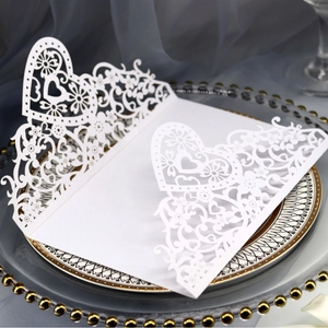 Elegant white laser-cut heart wedding invitation on decorative plate with gold accents
