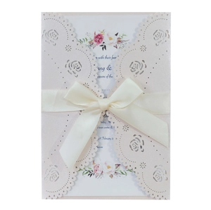 Detail of laser-cut rose hollow invitation card with pearlescent pink finish and ribbon bow