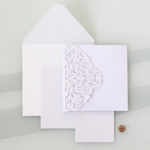 Macro view of white laser-cut floral wedding invitation set with envelope and blank inserts