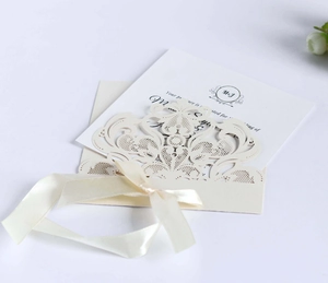 Detailed macro view of laser-cut lace pattern and silk ribbon on cream invitation card