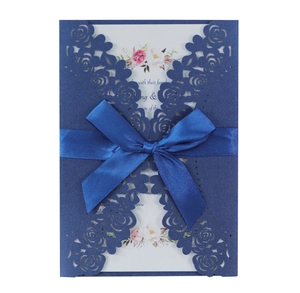 Detail of navy laser-cut rose invitation card with blue satin ribbon and floral insert
