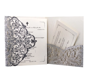 Macro shot of silver glitter laser cut wedding invitation with intricate lace hollow pattern