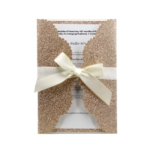 Macro detail of laser-cut glitter 40th birthday invitation with champagne gold silk bow