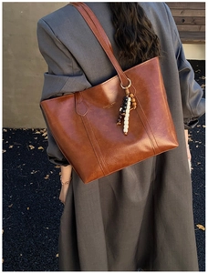 Brown vintage leather tote bag detail with colorful wooden beads on the strap