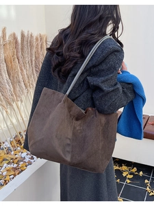 Détail d'un cabas en daim marron foncé avec coutures verticales et fine bandoulière