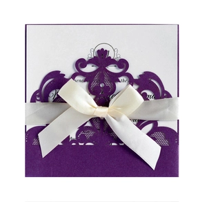 Detail of laser-cut lace wedding invitation with purple pearlescent paper and ivory bow