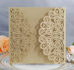 Macro shot of laser-cut gold lace invitation cover with detailed floral pearl paper texture