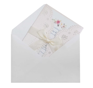 Detail of laser-cut rose wedding invitation set with silk ribbon and white envelope