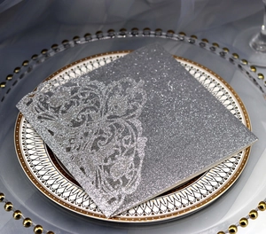 Macro shot of laser-cut silver glitter wedding invitation with intricate lace detail