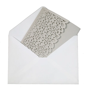 Detail of laser-cut geometric floral design on elegant white wedding invitation card set