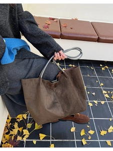 Vue détaillée du grand sac cabas en daim marron foncé avec anses grises sur fond automnal