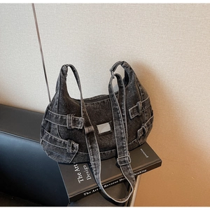 Close-up of black denim canvas messenger bag with metal buckles and industrial hardware