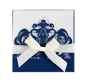 Detail of navy blue laser cut invitation with ivory ribbon bow for weddings and events