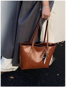 Close-up of brown vintage faux leather tote bag with stylish wooden bead accessory