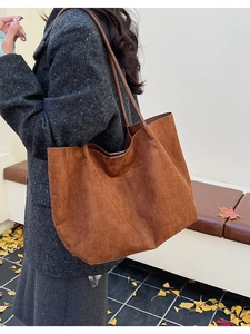 Grand sac cabas en daim marron porté par un mannequin dans un décor d'automne