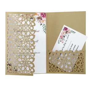 Elegant laser-cut gold wedding invitation with floral inner card on a white background