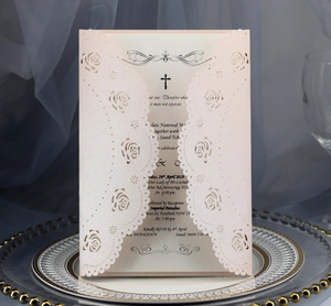 Detail of laser-cut rose hollow wedding invitation on glass tray with navy backdrop