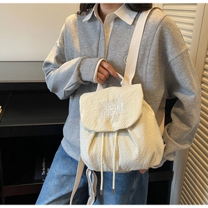 Detail of cream nylon backpack featuring texture fabric and YOU+ JI BEAR embroidery